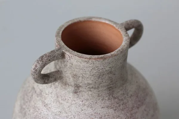 Detalle de jarrón de terracota con esmalte textura petrea color café claro y manchas marrón púrpura